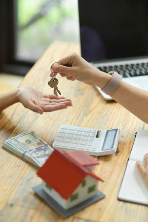 Female resident realtor giving a house keys to new owner after signing contract and paying the house depositの写真素材