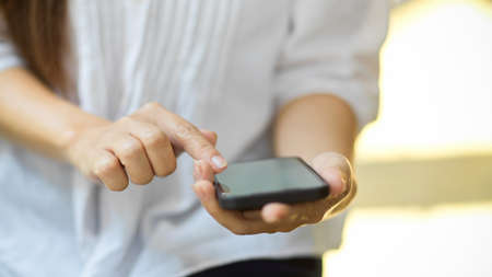 Close up, Senior woman's hands hold cellphone, using calculator app on mobile phone. blurred backgroundの写真素材