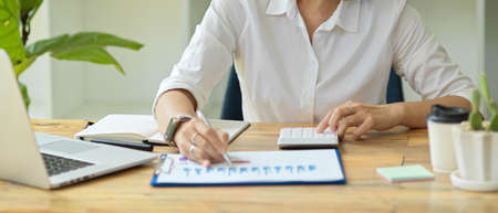Close-up of a female executive analysing and planning business sales performance from the latest financial data at her desk. Businesswoman working at her modern officeの写真素材