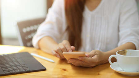Close-up Young female using smartphone, sitting at cafe. social media, browse internet, online shoppingの写真素材