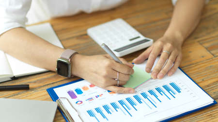 Closeup shot of businesswoman hand using pen and writing business idea lists in post note or sticky note, financial project, working in officeの写真素材