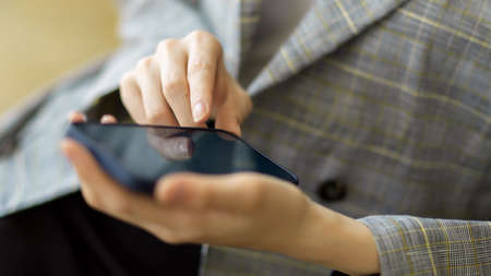 Close-up business woman in trendy suit using smart mobile phone to contact or online negotiation with business clientの写真素材