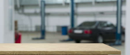 Empty wood counter or tabletop for montage your product display over blurred garage background. Maintenance and car repair serviceの写真素材