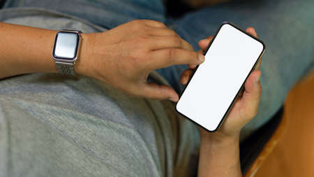 Male freelancer using smart mobile phone, relaxing while using mobile applications. Phone blank screen mockupの写真素材