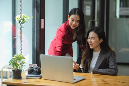 Two female business colleagues are discussing work and consulting business ideas on a laptop....