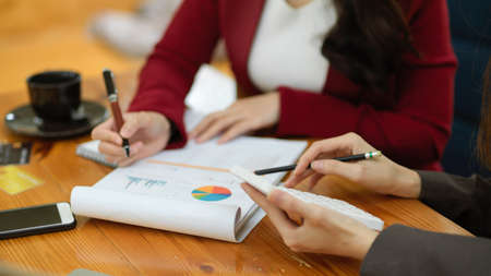 A team of business strategy consultants is working together, reviewing financial report papers and calculating business budgets. cropped imageの写真素材