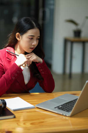 Successful young business women concentrated on her laptop computer in office, thinking or focusing on a project.の写真素材