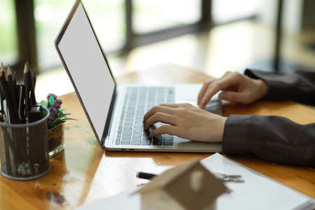 Side view of a female realtor working on laptop computer, typing rental contract on laptop. laptop blank screen mockup.の写真素材