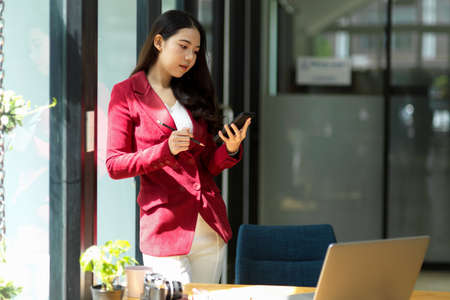 Successful business woman in the office looking on smartphone. Business female entrepreneur reading message on modern mobile phoneの写真素材