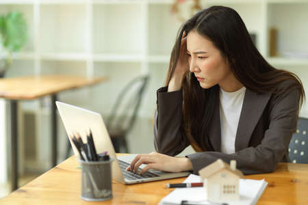 Stressed-out businesswoman is having IT problems with her laptop computer, is disappointed with the result of her work, and is looking for business solutions.の写真素材