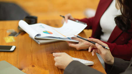 Cropped image of a female professional executive reviewing financial report papers in a meeting.の写真素材