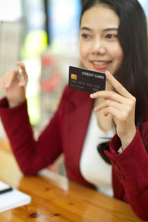 Portrait of Happy business woman hold credit card and bitcoin token, focus the objects and blurred background.の写真素材