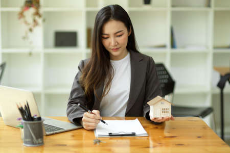 Beautiful asian real estate realtor working in the office, reviewing rental contract on papers. Property consultant working in a modern office.の写真素材