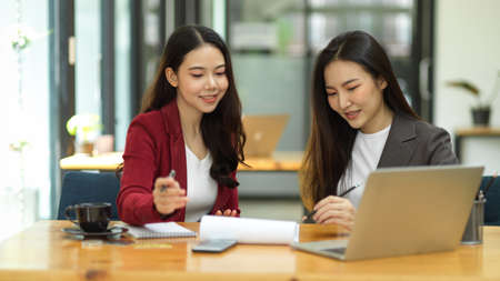 Two of business workers working, brainstorming and analysing competitor marketing strategy together in the officeの写真素材