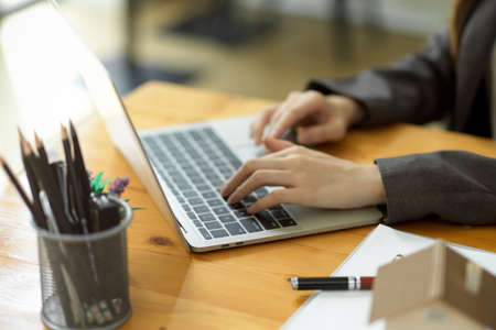 Cropped shot of millennial businesswoman or female employee working on laptop computer, typing on keyboard.の写真素材