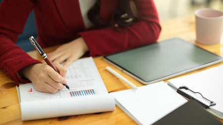 Close-up image of Smart businesswomen working in office, writing and reviewing business data paperworksの写真素材