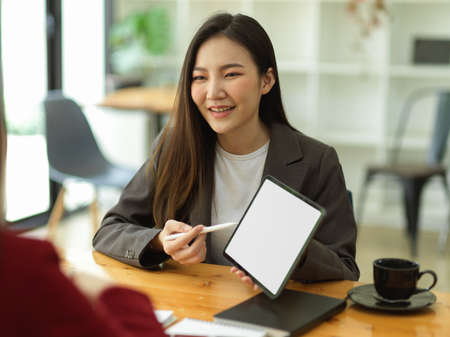 Asian businesswoman using digital tablet to explains and presents her business ideas to her colleagues in the meeting. tablet blank screen mockupの写真素材