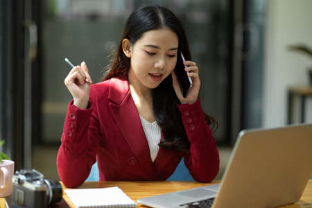 Young pretty female consultant working in the office and calling to a client to give a business advice.の写真素材