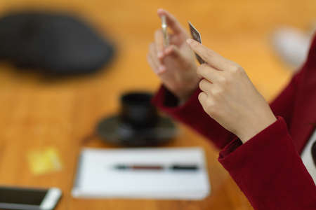 Side view of Female holding credit card, blurred workspace in the background. internet banking, online shopping and payment concept.の写真素材