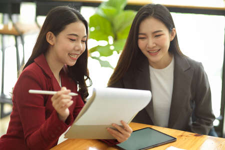 Businesswomen in the office brainstorming and discussing a new marketing strategy to engage with customer. Teamwork and partnership concept.の写真素材