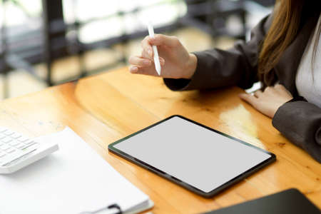 Cropped shot of business woman working on digital tablet computer in co-working space, tablet white screen mockup.の写真素材