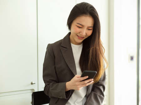 Young asian hipster businesswoman using smartphone message to her friends, chat, social media, connection.の写真素材