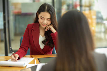 Happy young businesswomen sits in the office and works together, office atmosphereの写真素材