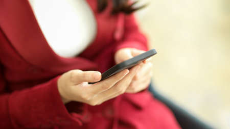 Cropped shot of Business female manager in red suit using mobile phone to checking business trends or reading a business email.の写真素材