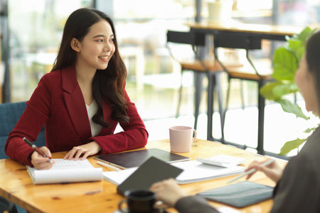 Attractive female business entrepreneur meeting with her business client partner at coffee shop, business negotiation, close the deal.の写真素材