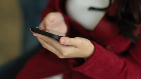 Close-up Elegant businesswoman in red suit using smartphone to message with her co-worker. wireless device technology.の写真素材