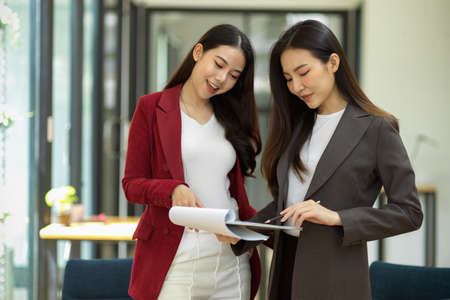Attractive businesswoman gives feedback to her employees, discusses, talks, and mentors them in the office. businesswomen working together.の写真素材