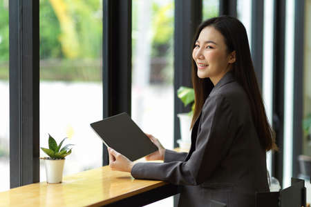 Successful asian businesswoman using portable digital tablet during quick lunch break at coffee shop.の写真素材