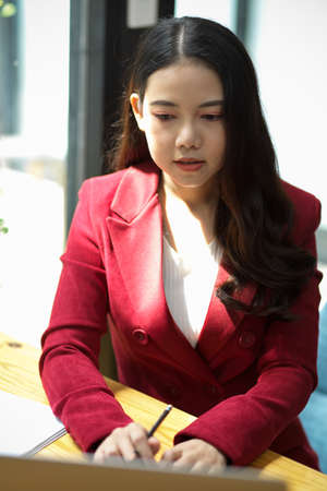 Serious confident young asian businesswoman working on laptop computer to making a business report.の写真素材