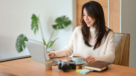 Positive young businesswoman working on laptop computer at home office space, work from home concept.の写真素材