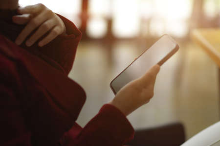 Side view, of Businesswomen in formal suit sits at her desk using modern smartphone to reading message, email or online news.の写真素材