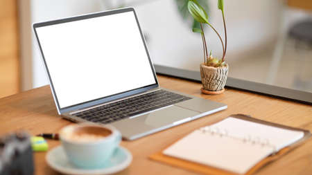 Closeup stylish workspace with modern laptop computer blank screen mockup, blank open notebook and decor on wooden table.の写真素材
