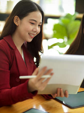 Young asian businesswomen working with statistics and checking financial report papers in a modern officeの写真素材