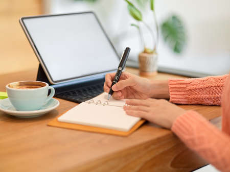 Close-up of a female college student doing her homework on a tablet computer, lecturing on notebook while studying online. tablet blank screen mockup.の写真素材