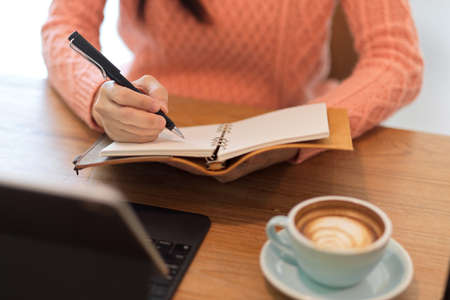 Cropped image of Female journalist, writer taking her ideas on notebook, checking list or managing her meeting agenda in personal diary.の写真素材