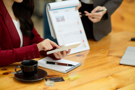 Cropped image of Two accountant checking financial statement or calculating business expenses and tax at the office desk.の写真素材
