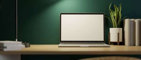 Close-up, Modern home workspace at night with laptop screen mockup and decor on wooden table over green wall. 3d rendering, 3d illustrationの写真素材