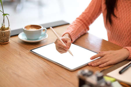 Close-up Female freelance graphic designer sketching her graphic digital photo art on modern tablet computer with stylus. tablet blank screen mockupの写真素材