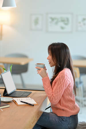 Portrait of Pretty and charming young woman relax and enjoy with her coffee during working on her task at coffee shop.の写真素材