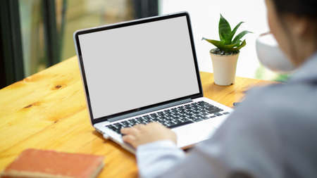 Businesswoman working on laptop computer at her desk, laptop blank white screen mockup for montage your graphic.の写真素材
