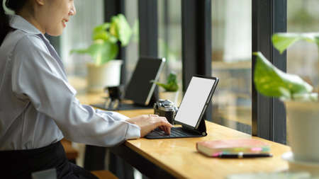 Side view, Pretty young businesswoman sits in co-working space and working on her portable digital tablet computer.の写真素材