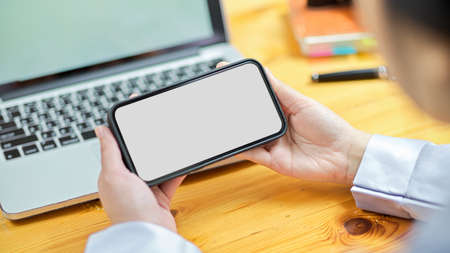 Close-up business female worker using modern smart mobile phone to watch online clip or play mobile game at the desk. smartphone screen mockupの写真素材