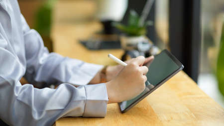 Close-up Businesswoman in formal dress sitting in coffee shop using stylus pen to drawing her business ideas on tablet computerの写真素材