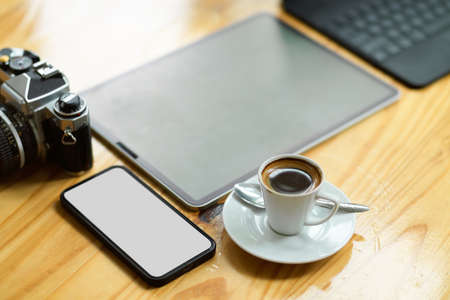 Modern digital tablet, smartphone, vintage camera and coffee cup on wooden table. wireless equipmentの写真素材