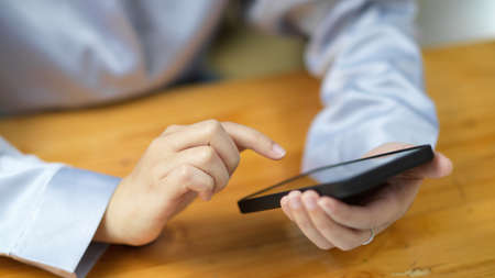 Close-up female hands tapping on smartphone screen. female using smart mobile phone to ordering delivery food on the apps.の写真素材