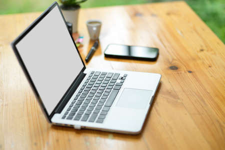 Side view, laptop computer blank screen mockup and mobile phone on wooden worktable in the office.の写真素材